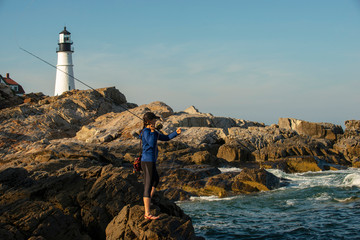 Woman fly fishing near Portland Headlight in Maine