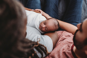 Mid-30?s multiracial couple holding their swaddled infant