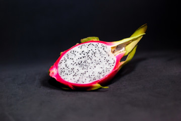Exotic fruits: half ripe pitahaya on a dark background