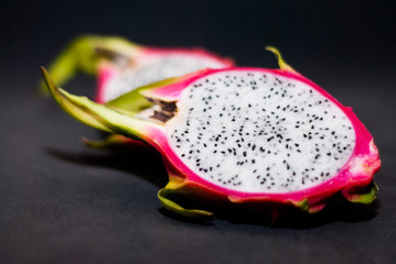 Two halves of ripe pitahaya on a dark background
