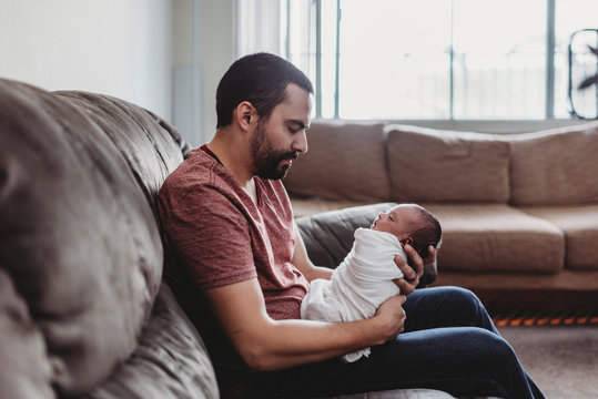Mid-30?s dad with beard holding swaddled infant