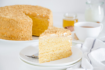 Honey cake. Traditional layered Russian cake Medovik with sour cream on a white plate on a white background. Horizontal orientation. Close up.