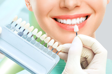 Close up portrait of Young women in dentist chair, Check and select the color of the teeth. Dentist makes the process of treatment in dental clinic office. Teeth whitenning