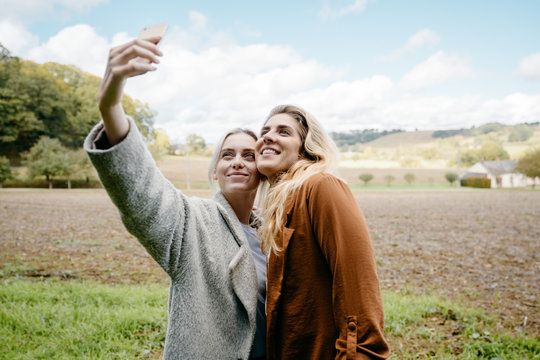 Two female friends taking a selfie in a French countryside landscape