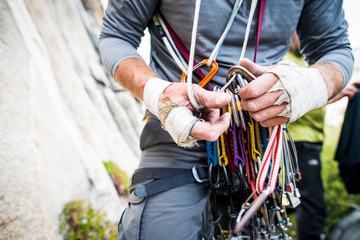 Rugged climber hands sorting through climbing gear