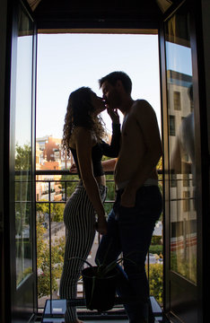 Couple kissing at home standing in the frame with the window open