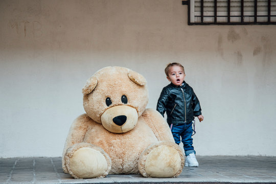 A Little Boy Playing With A Giant Teddy Bear.