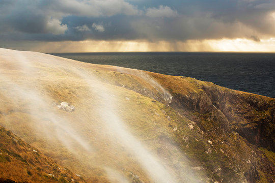 Moorland stream waterfalls on the coast at Stoer in Assynt, Scotland, UK, blowing uphill in storm force winds.