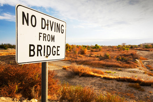 A no diving sign next to the dried up river bed of the Kern River in Bakersfield, California, USA. Following an unprecedented four year long drought, Bakersfield is now the driest city in the