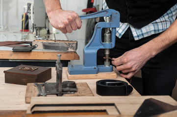 Close up, master work with press machine, tool and leather fittings.