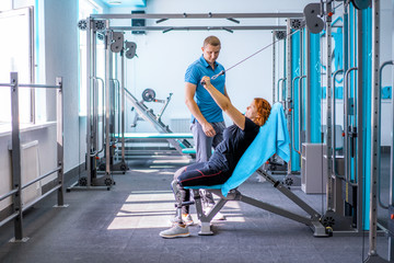 Personal trainer assisting woman with disabilities in her workout