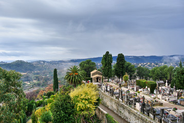 Saint-Paul-de-Vence / Provence - Alps - French Riviera, France - View from the observation deck of green and yellow trees, a cemetery and alpine mountains are also visible.