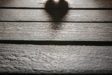 The shadow of heart on a wooden background. Latent love concept.