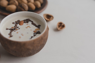 A healthy breakfast of granola, oatmeal, cereals, nuts and milk. Cups with granola, a jug of milk, a plate with nuts on a white background.