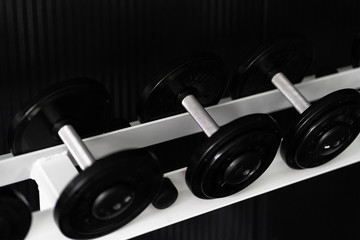 Obraz na płótnie Canvas Black dumbbell set. Close up many metal dumbbells on rack in sport fitness center , Weight Training Equipment concept.Indoor gym training for fitness activity or bodybuilders.