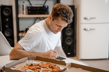 Man using phone delivering pizza from website on application. Phone application, modern technology. Online food delivery service. Pizza lover, junk food, fast food concept, unhealthy lifestyle. 