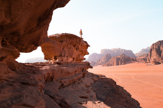 Young man is to the top of cliff. Wadi Rum also known as The Valley of the Moon is a valley cut into the sandstone and granite rock in southern Jordan to the east of Aqaba.