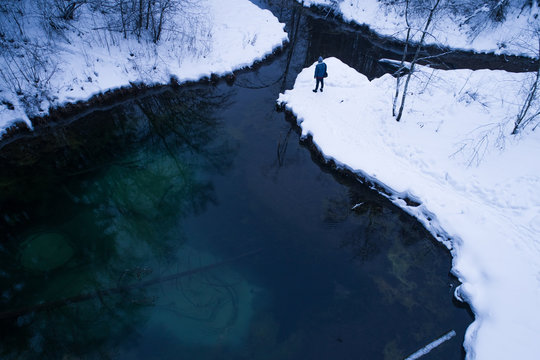 Aerial view of a man watching a water spring surrounded by snow Siniallikad Saula, Harju County, Estonia