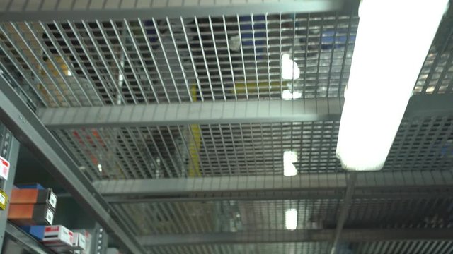 Walking On Metal Gratings Floor Storey Unrecognizable Warehouse Worker With Box Legs Feet Look Up View Tracking Camera Movement