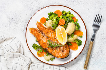 Grilled salmon fish steak with vegetables on white.