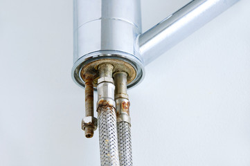 Old rusty pipe at the end of a water tap on a white background.