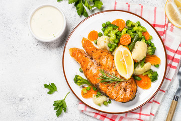 Grilled salmon fish steak with vegetables on white.
