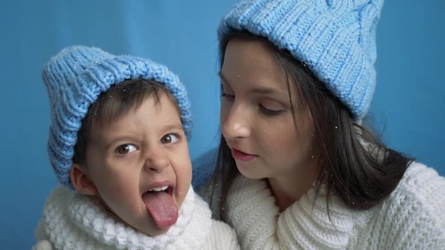 mother and son in blue knitted warm hats and white sweaters in the snow