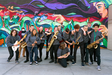 High school jazz band musicians in front of urban graffiti mural