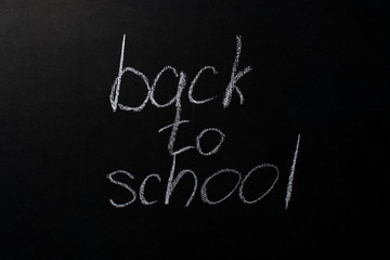 back to school written in white chalk on a black chalkboard