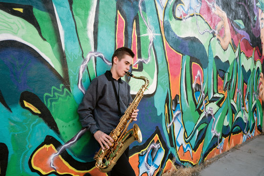 High school jazz band musician playing saxophone by graffiti