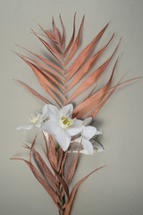 Fototapeta na wymiar Tropical dry leaves with white lilies on olive background. Closeup view