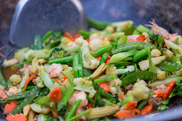 Stir fried vegetables in the pan. Mix vegetable on the cooking pan. Selective focus. Healthy stir fried vegetables in the pan and ingredients close up. Fried vegetables Thai style on black pan.