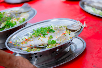 Steamed sea bass fish with lemon, Thai famous local food served on fish shape plate. Thai recommend...