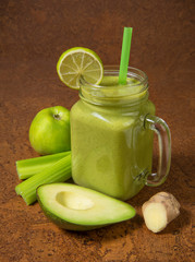 Smoothie avocado, celery and ginger in a glass jar on a brown background. Selected focus.