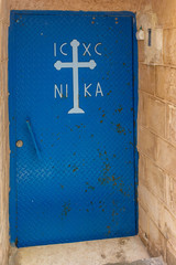 The ancient blue metal door with a cross