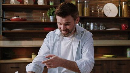 Indoor footage of a handsome middle-aged man resting at breakfast in the kitchen. Portrait of an amazed man reading exciting funny news on newspaper and smiling standing by table.