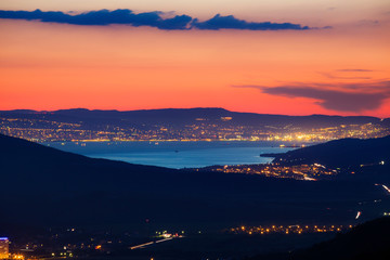 panorama of Novorossiysk Bay at night from the Caucasus mountains. bright lights, reflection in the water. car lights, mountains. roads. 