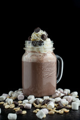 Big mug of hot cocoa with ice cream, whipped cream, chocolate chips and fluffy marshmallow
