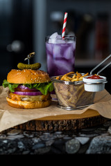 Close up view of a burger and fries with a purple Kombucha mocktail in behind.
