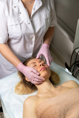 Beautician makes a procedure for a girl to improve facial skin condition