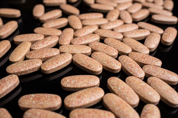 Pills scattered on a black background, close-up.
