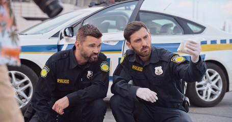 Police officers investigate an accident collect evidence in crime area. Two handsome serious...