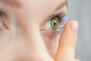 the girl holds on her finger and puts on a soft contact lens for one-day or planned replacement,...