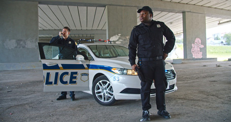 Young handsome policemen patrolling the city and protecting people. Afro american serious police...