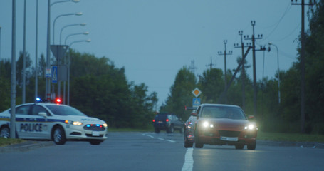 View of self-willed young man driving on modern sports car from the police. Police officer cop chasing a thief driving a patrol car on the highway at daytime. Police in pursuit.