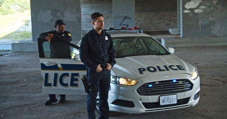 Danger in the city. Hurrying professional armed police officers run out of patrol car to the crime scene. Cops in action.