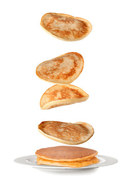 Plate with falling pancakes on white background
