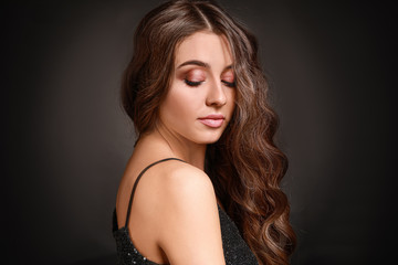 Naklejka premium Beautiful woman with curly hair on dark background