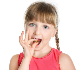 Little girl taking fish oil pill against white background