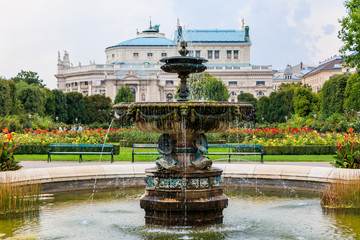 Fototapeta na wymiar Vienna, Austria - September 1, 2019: Fountain in the Volksgarten (People's Garden) in Vienna with a view on the state Theater Burgtheater, Austria